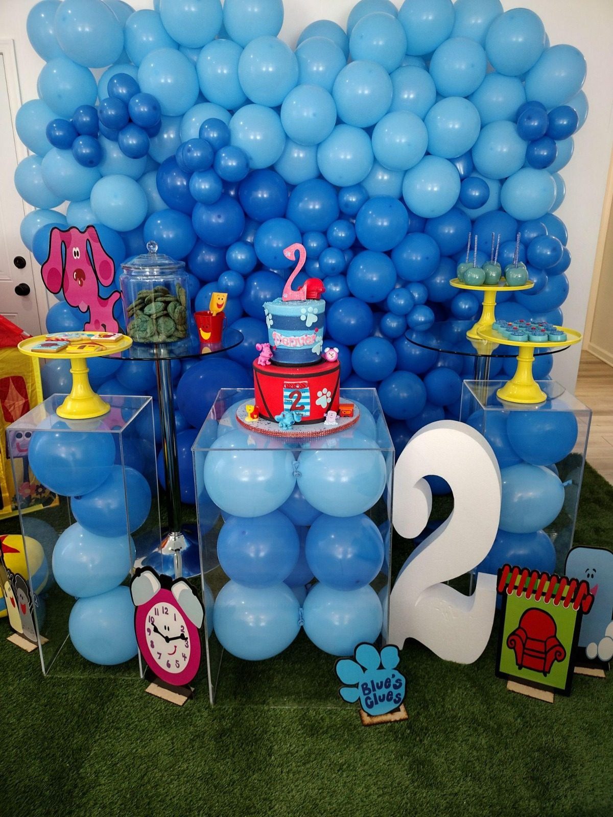A blue balloon wall behind a second birthday dessert table