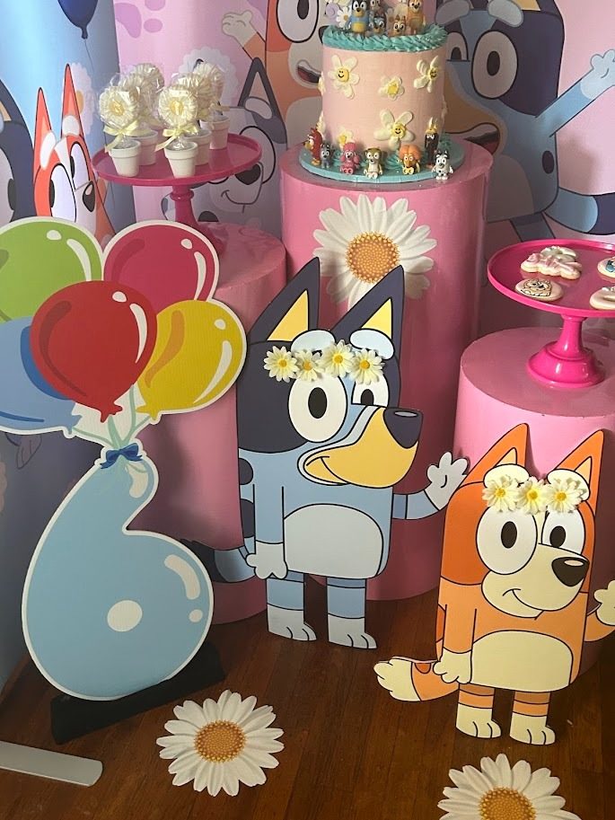 A cartoon themed birthday cake display with balloons